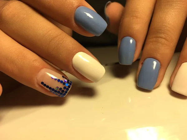 fashionable blue manicure with white design and blue pawns on a light background