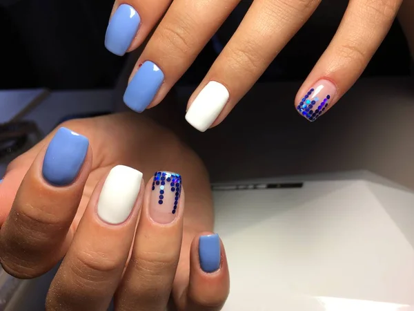 fashionable blue manicure with white design and blue pawns on a light background