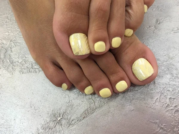 pedicure of yellow color with a fashionable design of stamping feathers