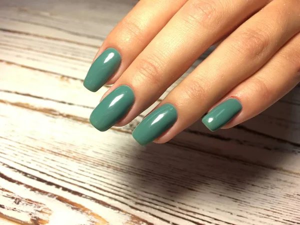 fashionable autumn green manicure on long square nails on a textured background