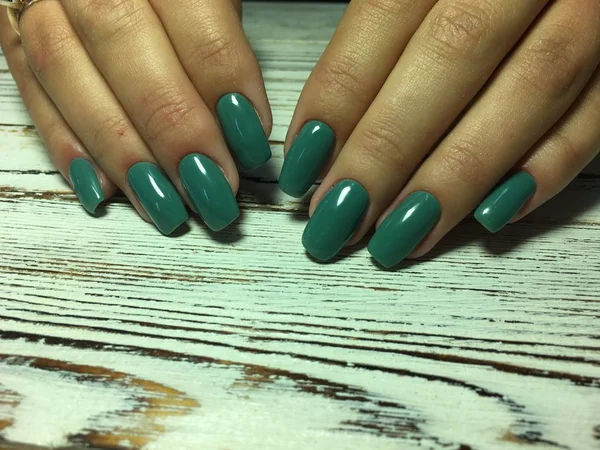fashionable autumn green manicure on long square nails on a textured background