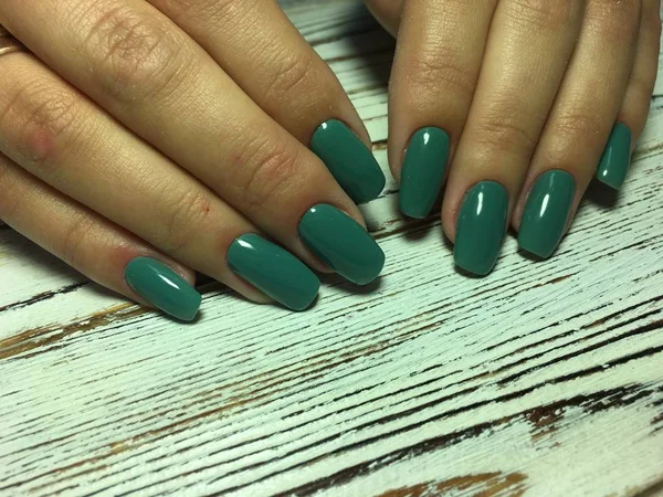 fashionable autumn green manicure on long square nails on a textured background