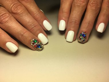 Şık beyaz manikür dokusal arka plan üzerinde renkli rhinestones ile.