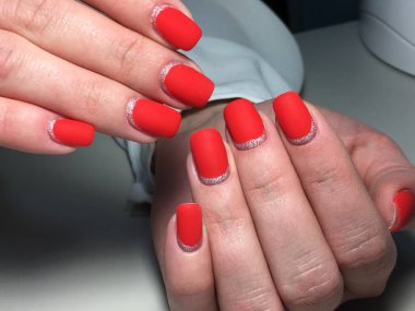 Gümüş ile dokusal bir arka plan üzerinde şık kırmızı mat manikür