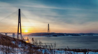 Taze kar ve uzun Askılı köprü Vladivostok, Rusya ile kış günbatımı görüntülemek