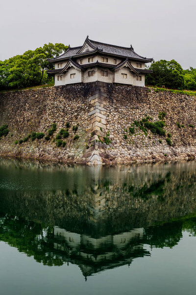 Осакские стены замка отражаются в воде
