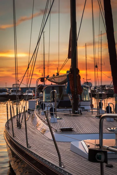 Sailboat with wooden deck standing in marine at beautiful sunset