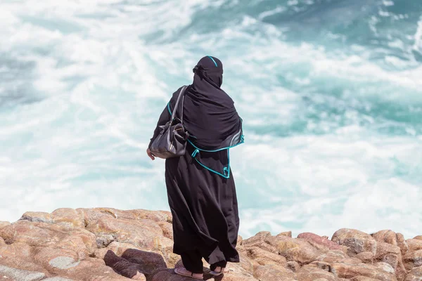 Büyük dalgalar Hermanus, Güney Afrika için bakarak geleneksel giysiler içinde Arapça kadın
