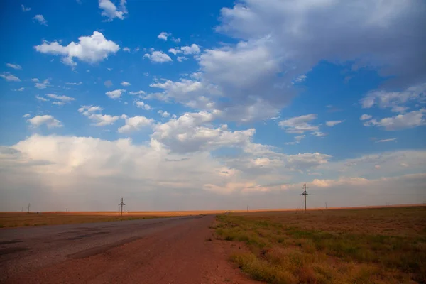 Highway. Blue with orange gradient sky with big clouds. Clouds cover the sun and droping sunrays down the earth