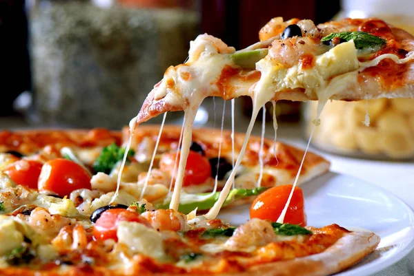 Slice of hot pizza large cheese lunch or dinner crust seafood meat topping sauce. with bell pepper vegetables delicious tasty fast food italian traditional on wooden board
