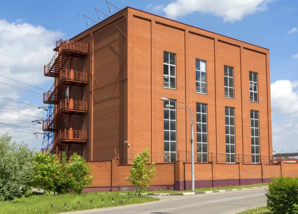 The building of a small factory of red brick. Production building with balconies. Summer