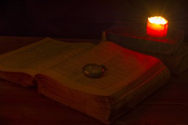 Kütüphanedeki eski kitap mum ışığında. Incil masada. Eski cep saati. Ortaçağ. Kehanet. Tahmin. Din