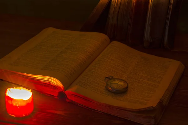 Kütüphanedeki eski kitap mum ışığında. Incil masada. Eski cep saati. Ortaçağ. Kehanet. Tahmin. Din