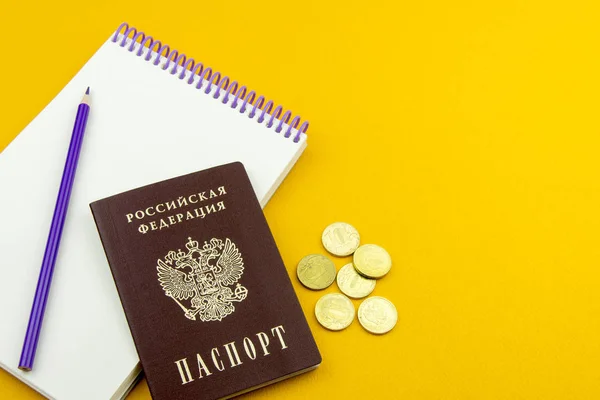 俄罗斯护照和几个硬币 橙色背景下的条目和铅笔的记事本 — 图库照片