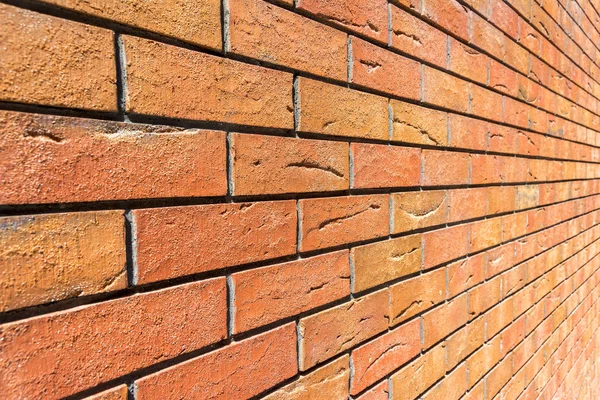 Red brick wall. Decorative brick with artificial defects and cracks. Angle view with perspective. Texture