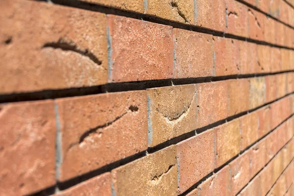 Red brick wall. Decorative brick with artificial defects and cracks. Angle view with perspective Texture