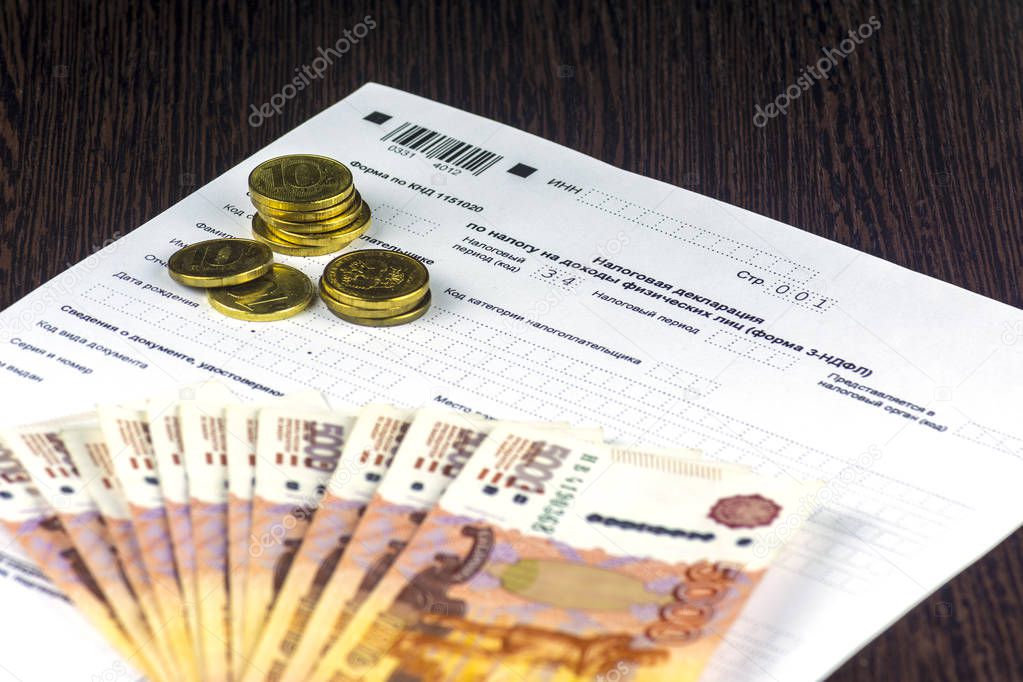 Russian annual tax Declaration of taxes of individuals. The Form 3-NDFL on the table. A few Russian notes and coins are on the sheet of the Declaration.