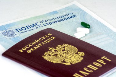 Rus sağlık sigortası ve Rus pasaportu ve mavi arka plan üzerinde birkaç hap yakın çekim