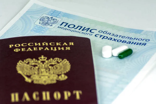 Rus sağlık sigortası ve Rus pasaportu ve mavi arka plan üzerinde birkaç hap yakın çekim