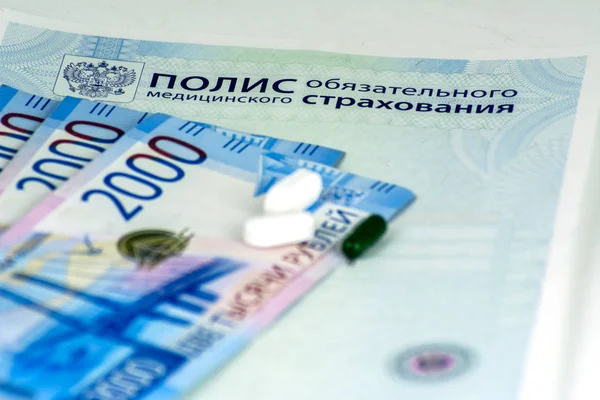Yakın çekim Rus sağlık sigorta poliçesi, Rus nakit banknot ve mavi arka plan üzerinde birkaç hap