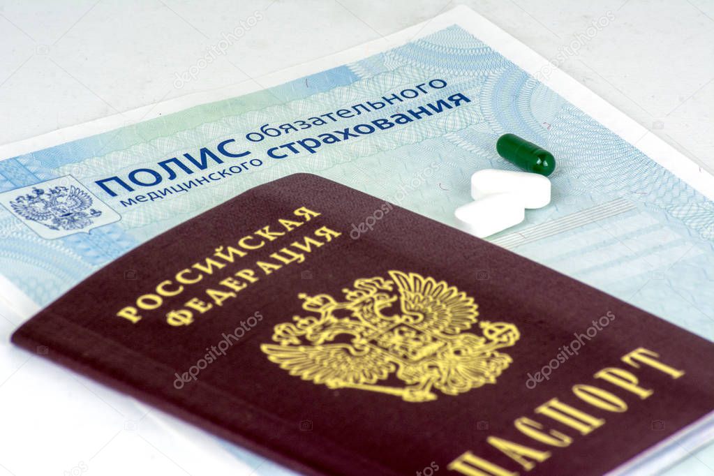 Close-up of Russian health insurance policy and Russian passport and a few pills on blue background