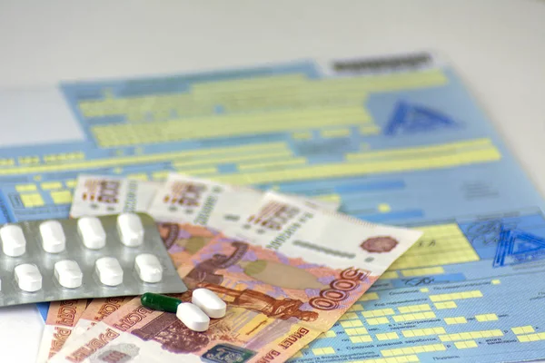 Rusya. Rus hastalık izni ile mühürler. Bir şişe hap ve toplu olarak birkaç hap. Rus para banknot 5000 ruble. En yakın hapları odaklanmak.