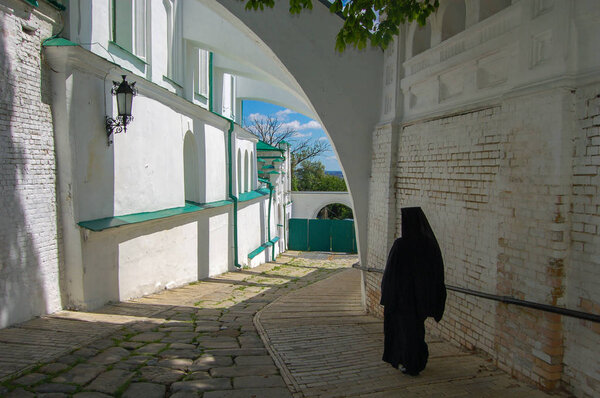 A monk in a black robe in a monastery. The Kiev Pechersk Lavra is a common name for an entire complex of cathedrals, bell towers, cloisters, fortification walls and underground caverns.