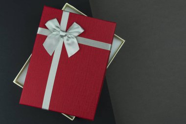 Siyah ve gri arka plan üzerinde yay ile açık güzel kırmızı hediye kutusu