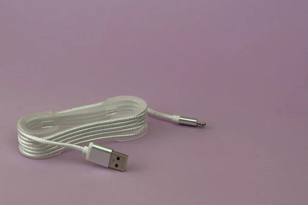 USB charging and cable for mobile devices on pink paper background.