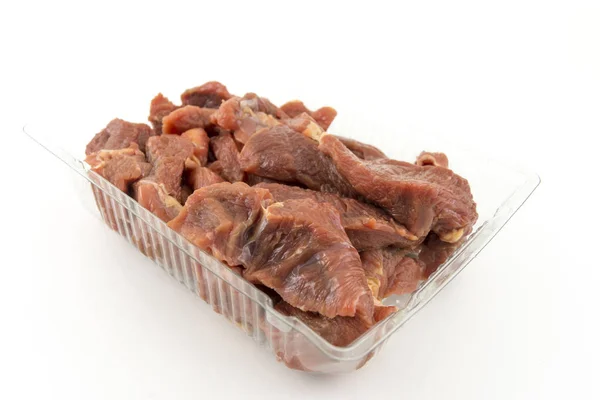 Raw pieces of beef, goulash in a plastic tray. On white background. — Stock Photo, Image