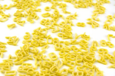 Beyaz üzerine dağılmış harfler ve sayılar şeklinde makarna