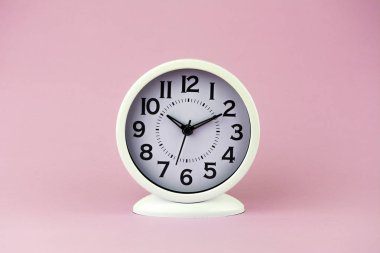 Pembe arka planda büyük sayılar ile beyaz çalar saat.