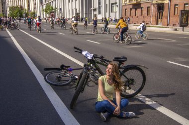 Moskova. Rusya. 19 Mayıs 2019. Moskova Bisiklet festivali Velofest 2019. Çok sayıda bisikletçi geniş bir cadde boyunca binmek. Yolda dinlenen kız bisikletçi.