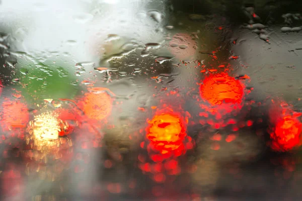 Yağmurda arabaların ışıklarında arabanın camından görüntüleyin. Isliç camda bulanıklık.