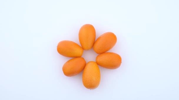 Montón de varios kumquats enteros. Girando sobre la mesa giratoria. Aislado sobre fondo blanco. Vista desde arriba / arriba . — Vídeo de stock