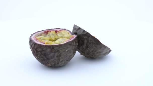 Two halves of passion fruit. Rotating on the turn table. Isolated on white background. Side view. — Stock Video