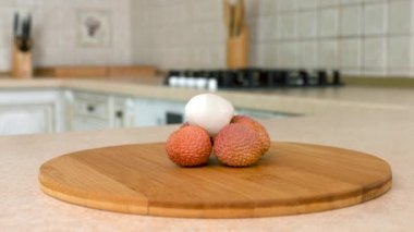 Birkaç bütün lychee kapatın. Fotoğraf makinesi ve arka plan üzerinde beyaz mutfak ile döner. Dolly-shot.