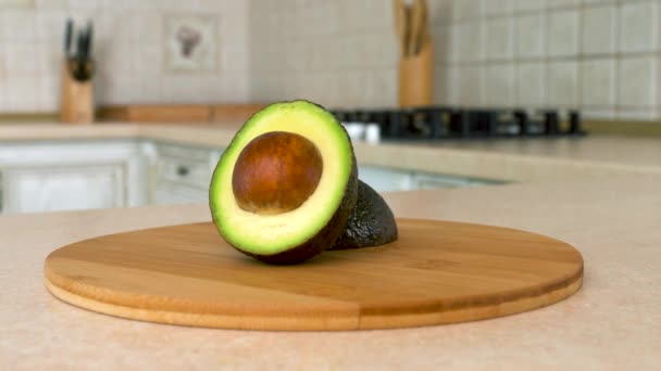 Nahaufnahme von in Scheiben geschnittener Hassavocado. Die Hälfte der Avocado. drehbare Kamera mit weißer Küche im Hintergrund. Dollyshot. — Stockvideo