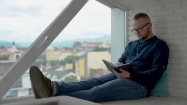 Genç adam pencerenin oturuyor. Not defterini yazıyor düşünülmüş bir adamdır. Eski şehir içinde belgili tanımlık geçmiş penceresinde.