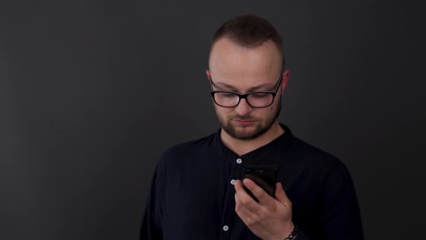 Young Bearded Man Glasses Studio Shot Male Looks His Phone — Stock Video