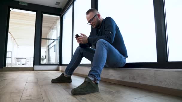 Депрессивный Молодой Человек Сидит Панорамного Окна Пишет Мобильном Телефоне — стоковое видео