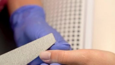 Manikürcü closeup makro bir müşteri ile eski tırnak cilası kaldırın. Orocessing testere çivi. El ile manikür sürecinde güzellik salonu.