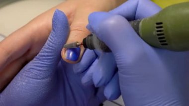 Closeup freze makinası - fraser çivi kullanarak eski tırnak Polonya kaldırmanın. Donanım manikür sürecinde güzellik salonu. Mavi glowes.