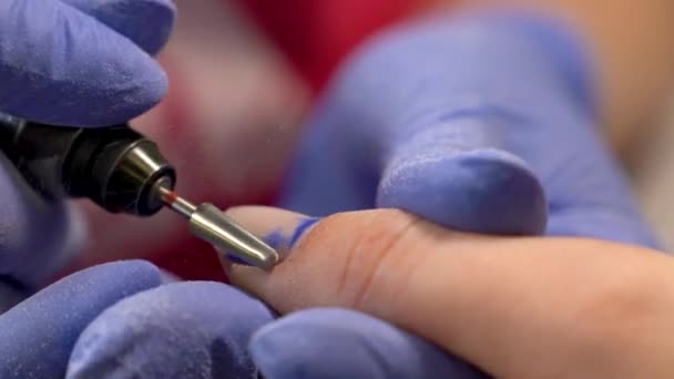 Μακροεντολή αφαίρεση παλιό βερνίκι νύχι χρησιμοποιώντας καρφί άλεσμα μηχάνημα. Διαδικασία μανικιούρ υλικού στο σαλόνι ομορφιάς. Μπλε glowes. — Αρχείο Βίντεο