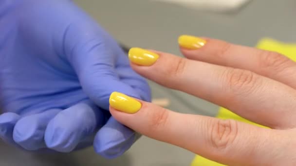 Closeup of fingernail shape correction using nail file. Yellow polish. Last manicure strokes. Beauty salon. — Stock Video