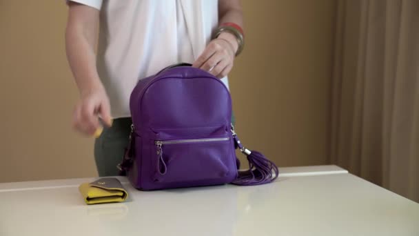 Een jong meisje spreidt zich uit de inhoud van haar tas op de witte tafel. Inhoud van dames tas. — Stockvideo