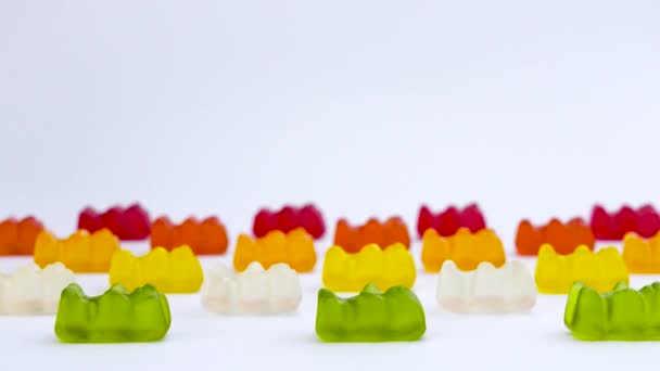 Popular gelatin candies shaped in the form of a bear are moving horizontally on the white background. — Stock Video