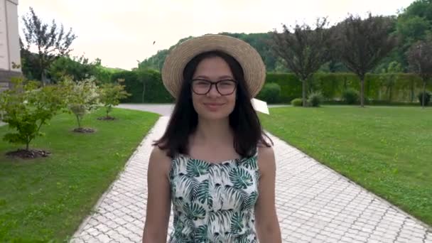 Lachende Aziatisch meisje in de hoed en de zomer jurk loopt langs het spoor in het park. Geniet van het leven — Stockvideo