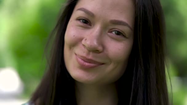 Een portret van een gelukkig uitziende Aziatische vrouw met een tranen van geluk en schattige glimlach. Close-up. — Stockvideo