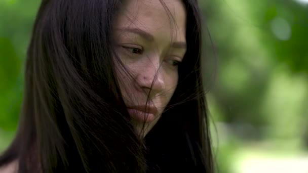 Een portret van een trieste Aziatische vrouw. Wind ontwikkelt haar haren. Hopeloosheid en depressie in haar ogen. — Stockvideo